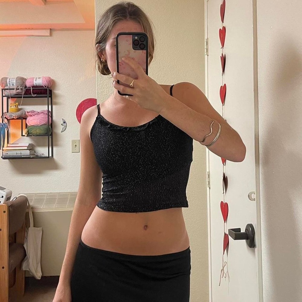 The black shiny cami tank top with ruffle detail on the hemlline